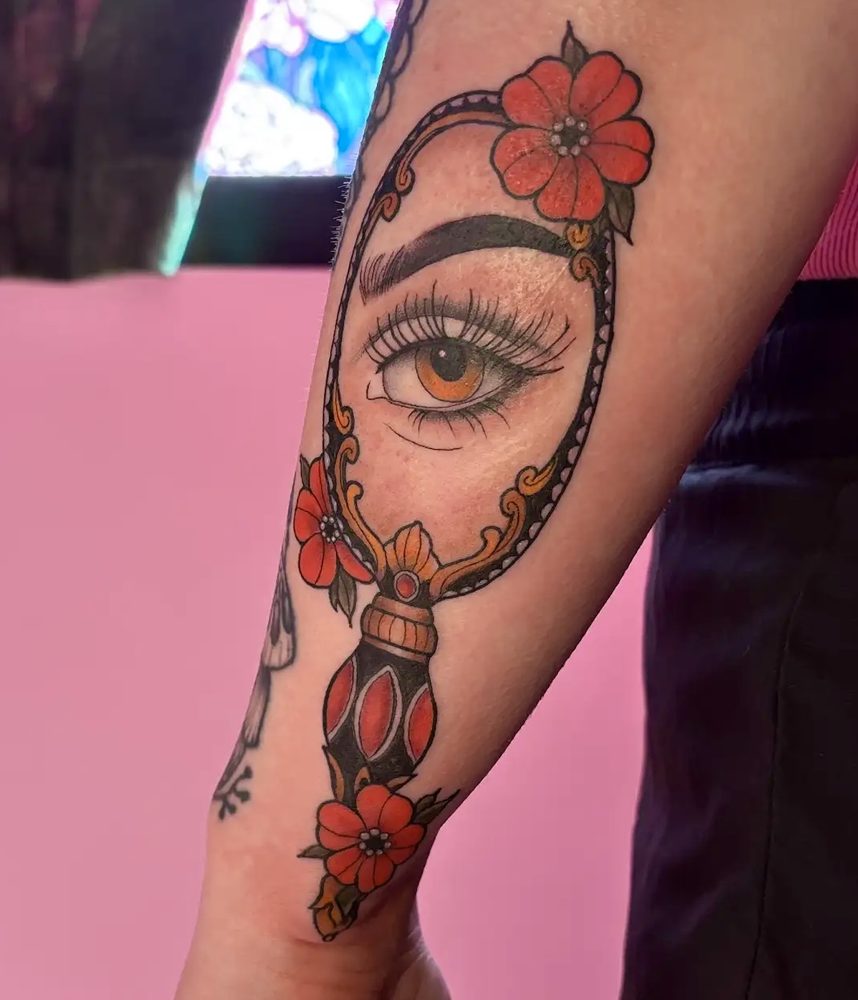 Traditional hand mirror reflecting an eye, framed with red flowers